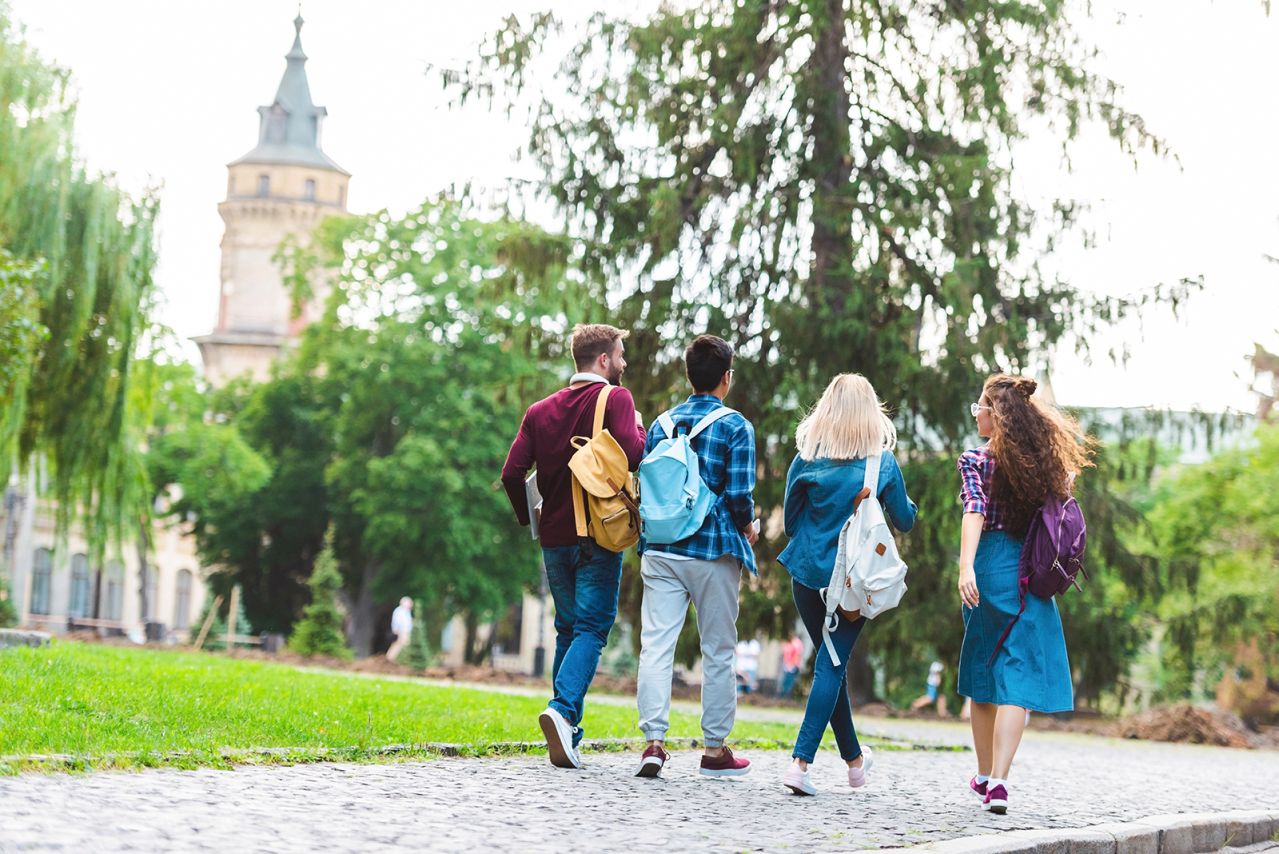 Four college students walking on a college campus.