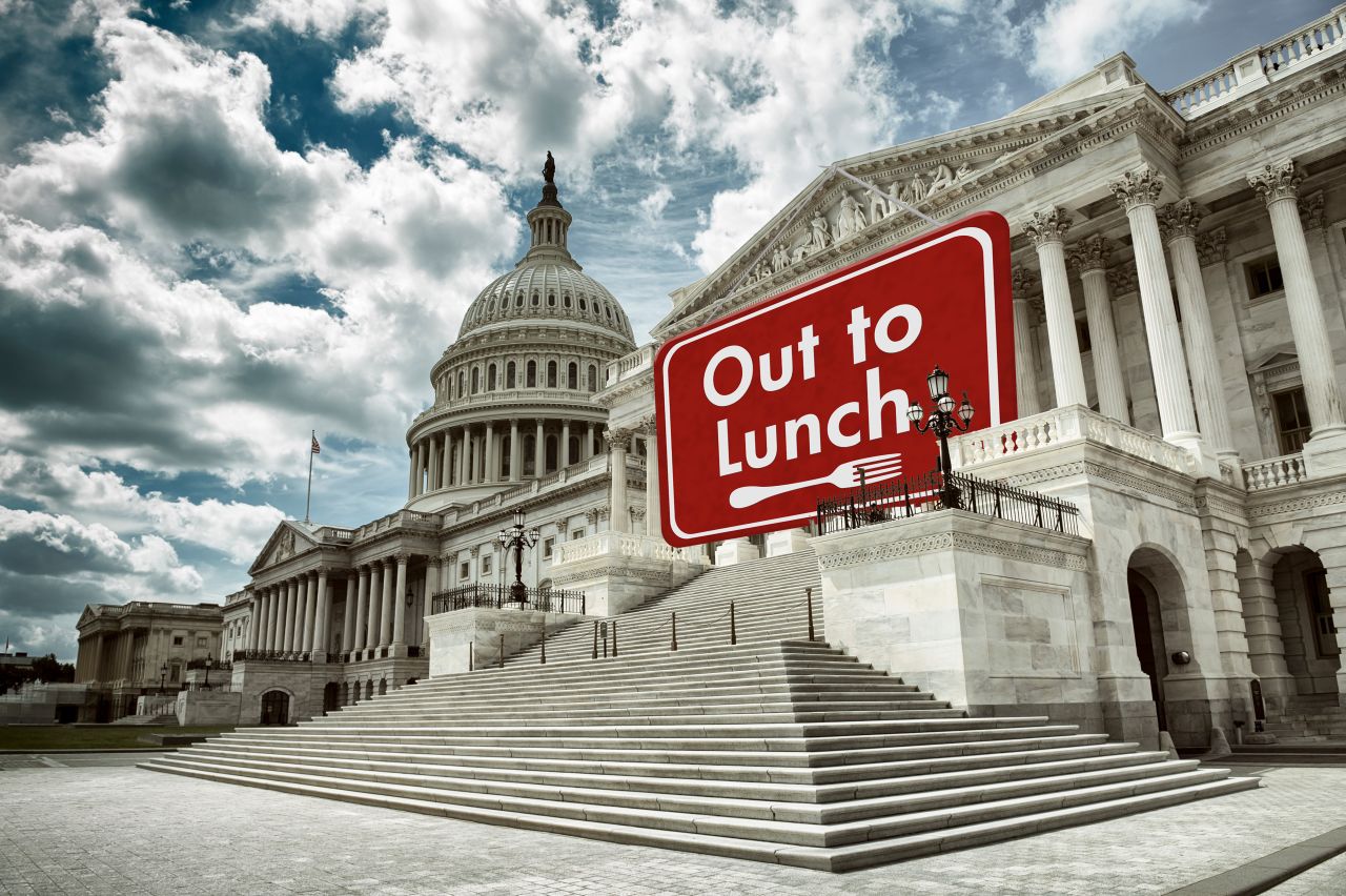 US Capitol Building with "Sorry, we're closed" sign hanging from roof.