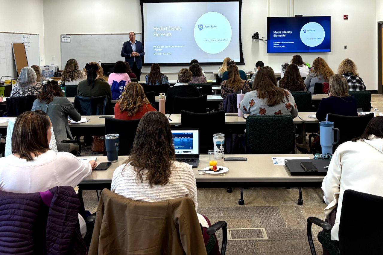 Professor and Director of the Penn State News Literacy Initiative, Matt Jordan stands at the front of a classroom of K12 educators before a projector screen with a slide that reads "Elements of Media Literacy."