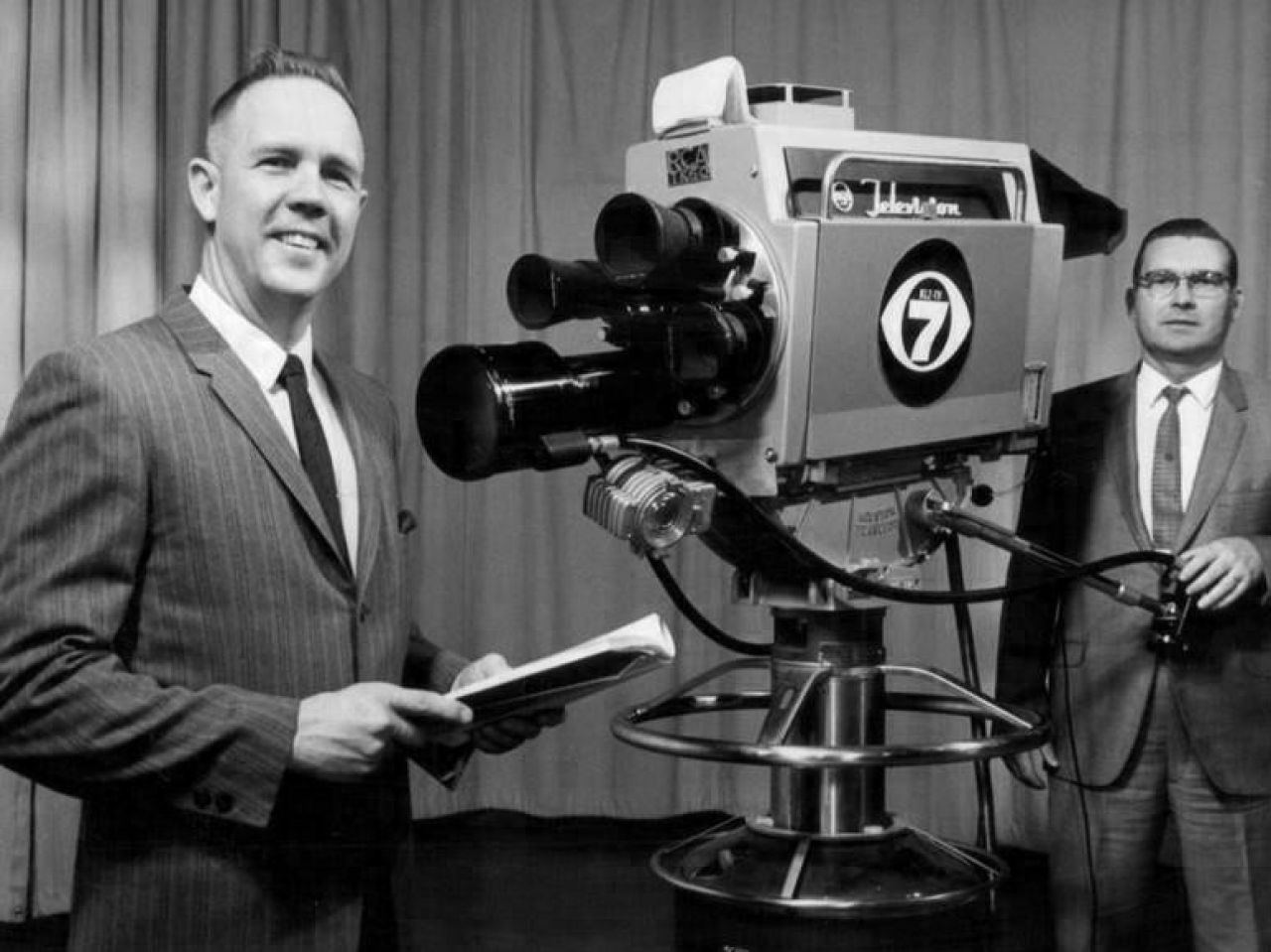Photo of the taping of a religious public affairs program at KLZ-TV, Denver in 1968. Two men in suits, one behind a vintage television camera.