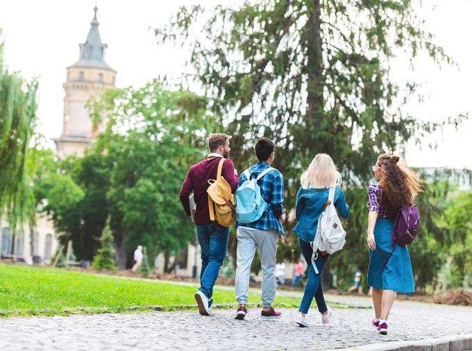 Four college students walking on a college campus.