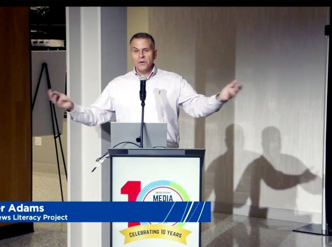 Peter Adams at podium with Media Literacy Week 10 Year logo.