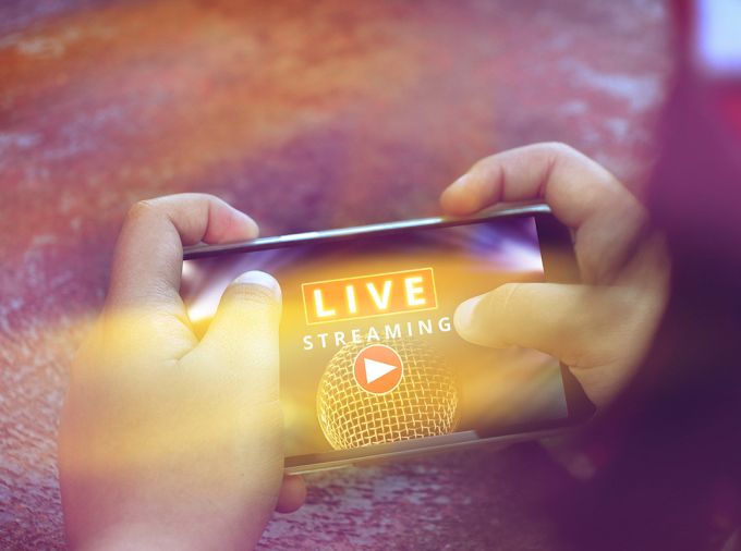 Hands holding phone in landscape orientation with "Live Steaming" on screen.