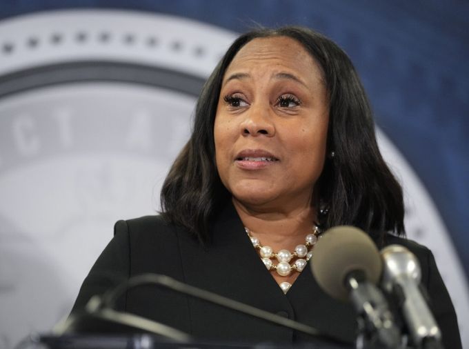 Fulton County District Attorney Fani Willis speaks into microphone at podium of Fulton County Government Center during a news conference.