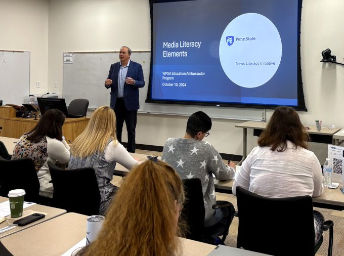 Professor and Director of the Penn State News Literacy Initiative, Matt Jordan stands at the front of a classroom of K12 educators before a projector screen with a slide that reads "Elements of Media Literacy."
