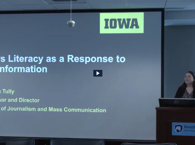 Melissa Tully at podium with back to a screen with projected slide with the title of her presentation.