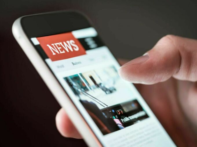 hand holding smart phone on news website