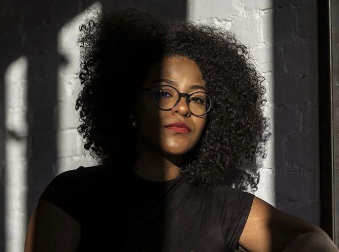 portrait Lyndsay Green partially in shadow, holding chopsticks at a restaurant